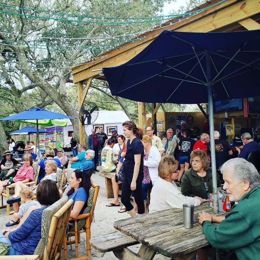 Guests gathered under umbrellas and oak trees in The Courtyard at The Point Restaurant Perdido